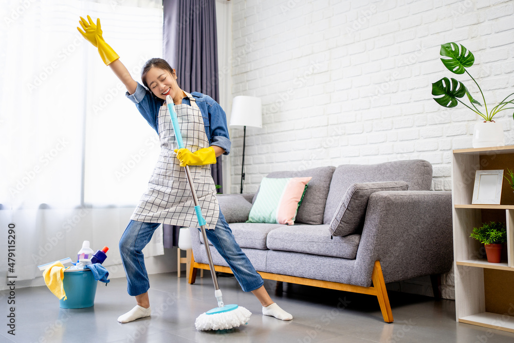 Happy young Asian woman cleaning her home, singing at mop like at ...