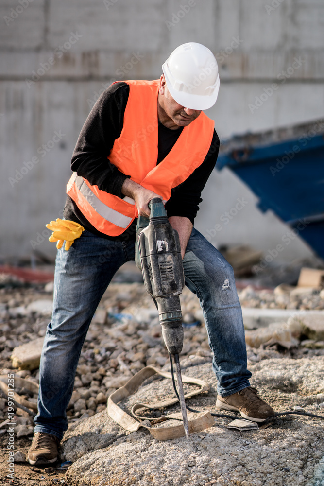 Male construction worker using a jackhammer on construction site ...