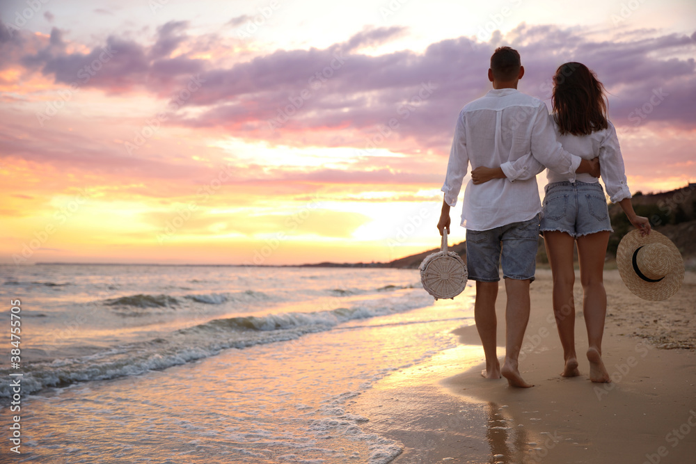 Lovely couple walking on beach at sunset, back view. Space for ...