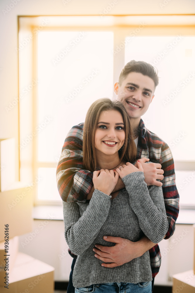 Cute couple hugging and smiling in their new home. Moving to new ...