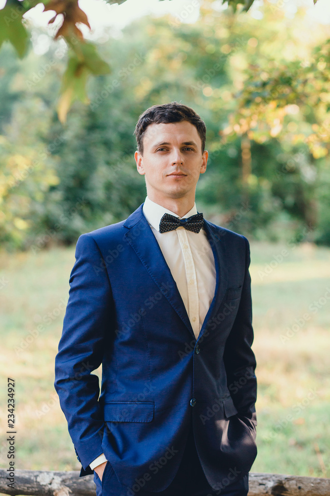 A cute young and attractive groom, dressed in a blue wedding ...