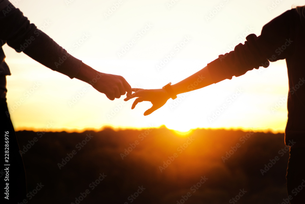 Romantic couple holding hands and watching a beautiful sunset ...