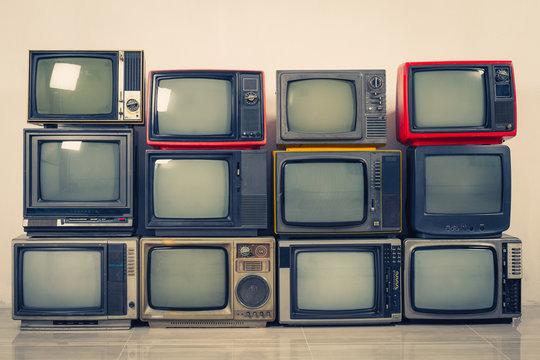 Retro old TVs pile on floor in the room. Television stack with ...