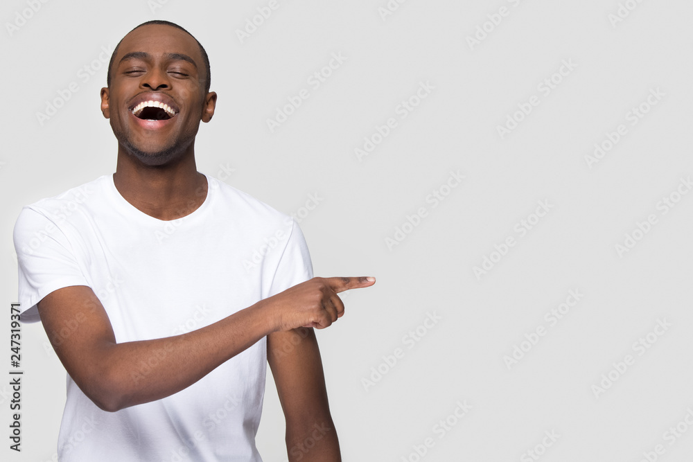 Happy african man laughing out loud at funny joke pointing finger ...