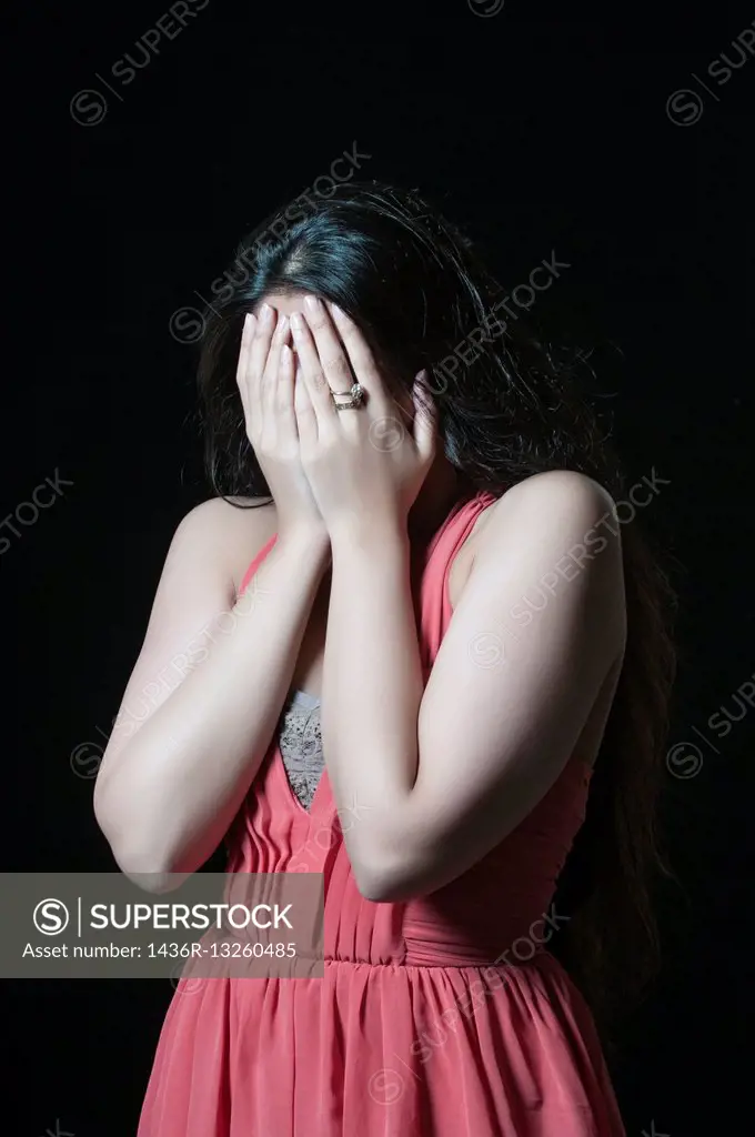 Sad woman hiding face with hands crying. - SuperStock