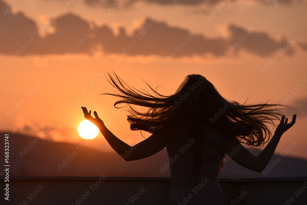 Stock-Foto „Sunset and silhouette of a girl with long hair looking ...