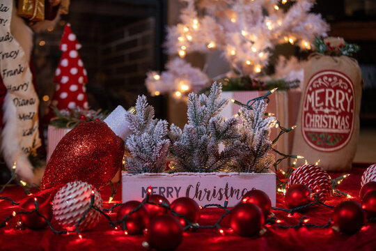 Festive Christmas centerpiece with a wooden Merry Christmas box, frosted pine branches, red ornaments, and fairy lights.