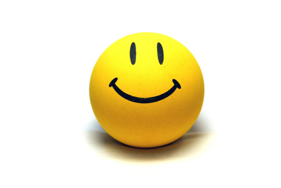 Bright yellow stress ball with a simple black smiley face, isolated on white background.