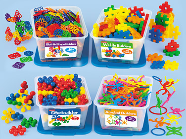 Four colorful educational building toy sets in clear bins-Stick-A-Shape, Waffle, Starbuilder, and Assorted Builders-spilled for creative play.