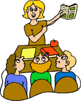 A smiling teacher holds up a book while three students sit at a desk, engaged in a classroom lesson.