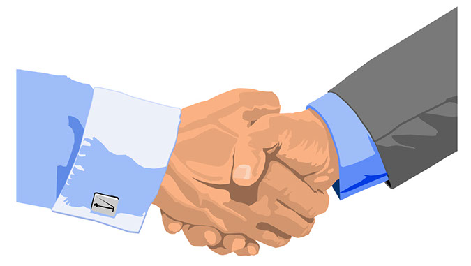Two professionals in business attire shaking hands, symbolizing agreement or partnership.