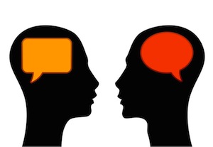 Two silhouetted heads facing each other with orange and red speech bubbles, symbolizing communication or dialogue.