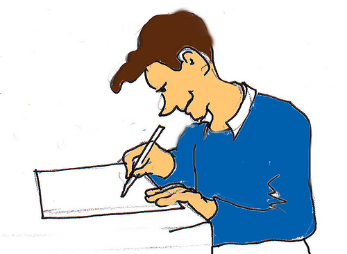 A man in a blue sweater writes on a document with a pen, focused and smiling.