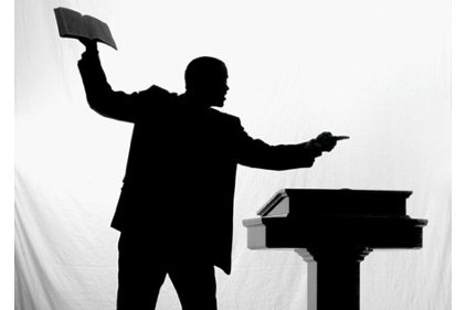 Silhouetted speaker holding Bible aloft and gesturing from a podium, evoking passionate preaching or religious teaching.