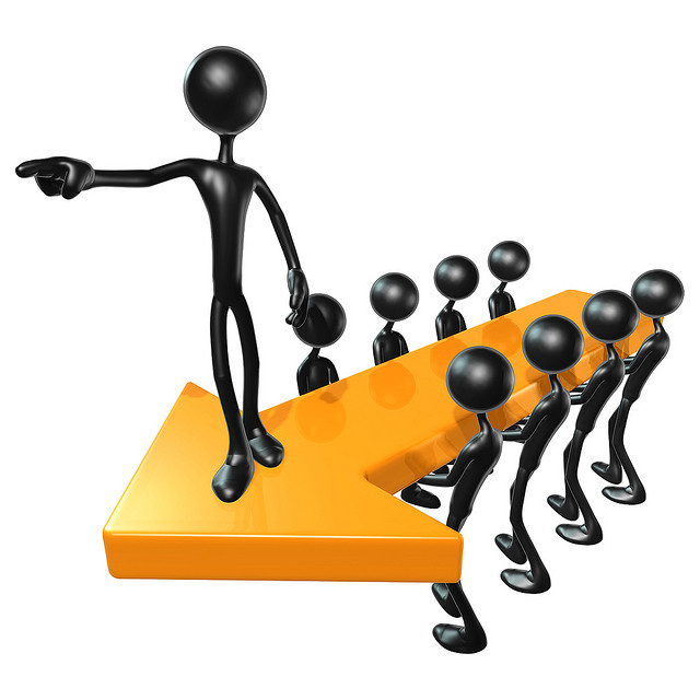 Black 3D figures walking on a large orange arrow, led by a pointing leader figure.