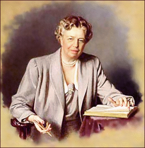 Portrait of Eleanor Roosevelt seated at a desk, holding a pen and open book, dressed in a light gray suit with pearl necklace.