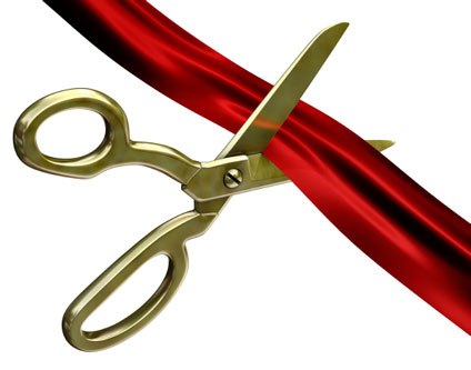 Golden scissors cutting a glossy red ribbon against white background, symbolizing grand opening or launch event.