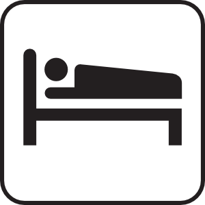 Simple black-and-white icon of a person lying on a bed, representing sleep or accommodation.