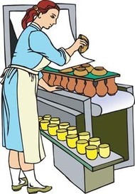 A baker in a blue apron places freshly baked pastries onto a tray beside yellow custard cups on a conveyor belt.