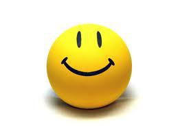 Bright yellow smiley face ball with simple black eyes and curved smile on white background.
