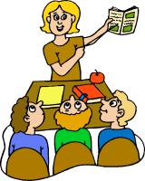 A smiling teacher holds up a book while three students sit at a desk, attentively listening in a classroom setting.