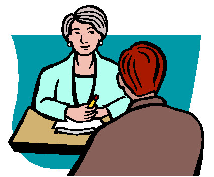 A professional woman with gray hair consults a client across a desk, holding a pencil and papers.