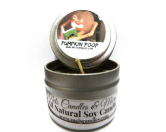 A small tin candle labeled "Pumpkin Poop" with a cartoon illustration on the lid, featuring a natural soy wax candle inside.