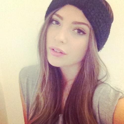 Young woman with long ombre hair wearing a black knitted beanie, looking at the camera with soft expression.