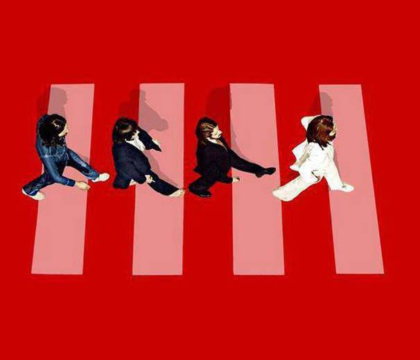Four women in stylish outfits stride across a pink zebra crossing on a bold red background, evoking iconic album cover art.