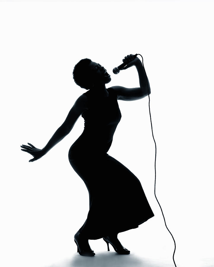 Silhouette Of Female Singer Singing On Microphone by PM Images 