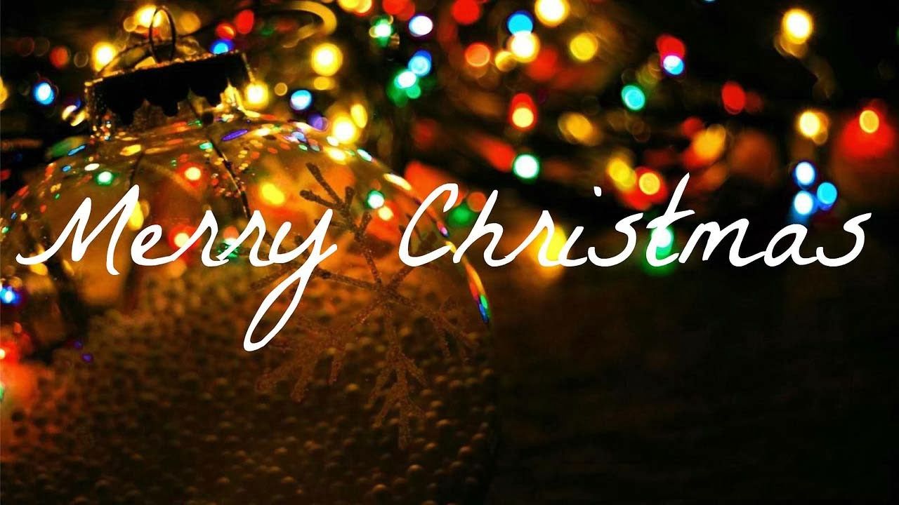 Shiny Christmas ornament with snowflake design, glowing multicolored lights in bokeh background, and "Merry Christmas" script overlay.