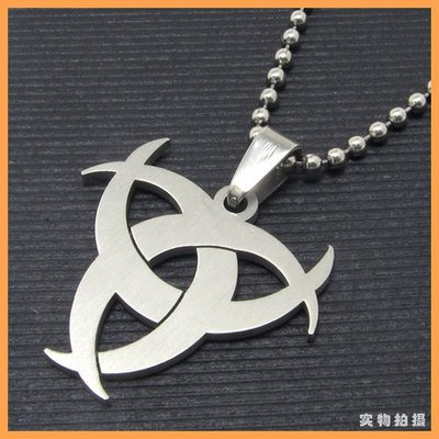 Stainless steel biohazard symbol pendant on ball chain necklace, photographed on dark textured background.