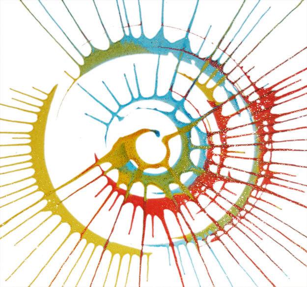 Vibrant multicolor paint splash forming a dynamic spiral pattern on white background, with red, yellow, blue, and green radiating outward.