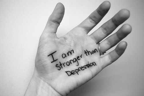 Open hand with "I am stronger than Depression" written on the palm, black-and-white photo conveying resilience and hope.