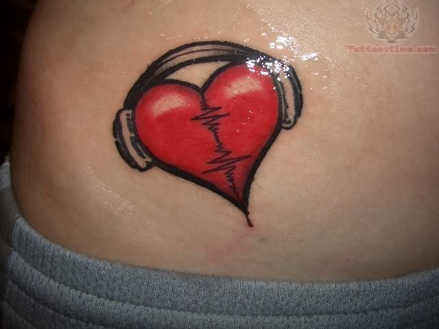 Red heart tattoo with headphones and EKG line on skin, fresh ink shine visible