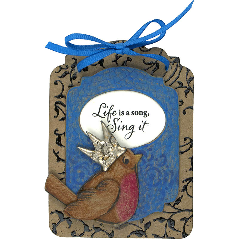 Handcrafted tag with a robin wearing a silver crown, blue ribbon bow, and the phrase "Life is a song, Sing it" on a textured background.