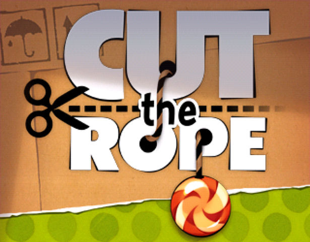 Scissors cutting a rope with "CUT the ROPE" text and a candy dangling below on cardboard background.