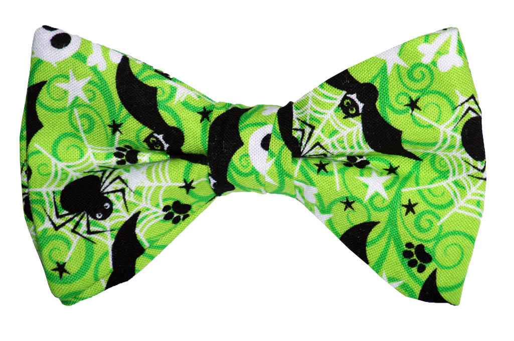 Lime green Halloween bow tie with black bats, spiders, paw prints, and white spiderwebs on a festive patterned fabric.
