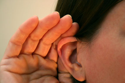 Close-up of a person cupping their hand to their ear to listen more intently.