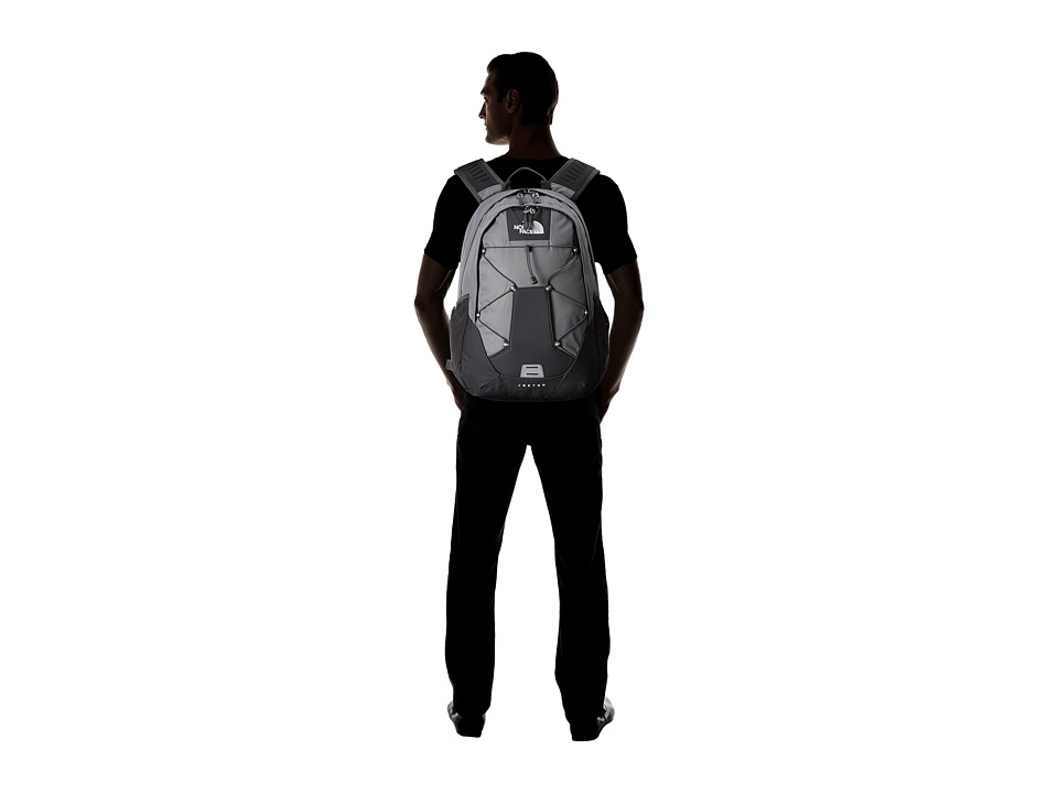 Man wearing a gray and black The North Face backpack, viewed from behind against white background.