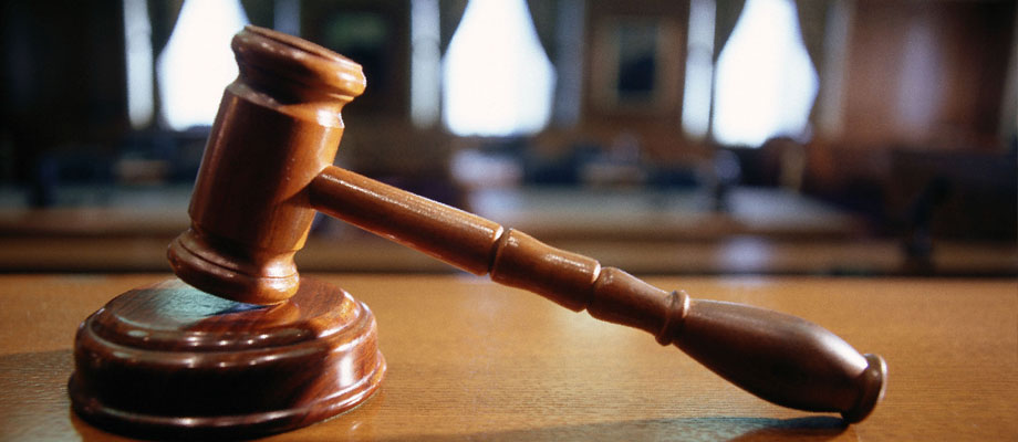 Wooden judge's gavel resting on sound block in a courtroom setting