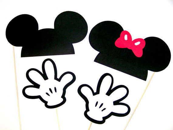 Black Mickey and Minnie Mouse silhouette cutouts with gloves and a pink bow on sticks, for party photo props.