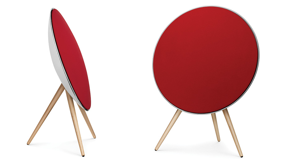 Red circular wireless speaker with wooden tripod legs, shown from side and front views on white background.